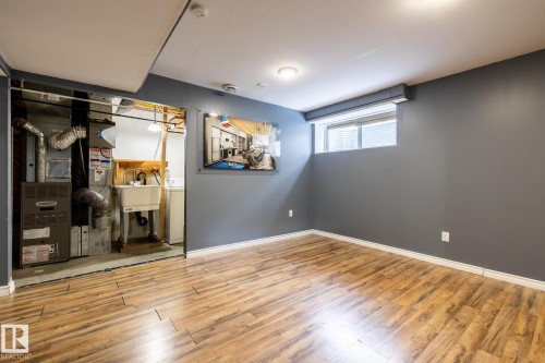 Basement with light wood-type flooring, heating unit, and washer / dryer - 11622 11 Avenue, Edmonton, AB - Indoor Photo Showing Other Room
