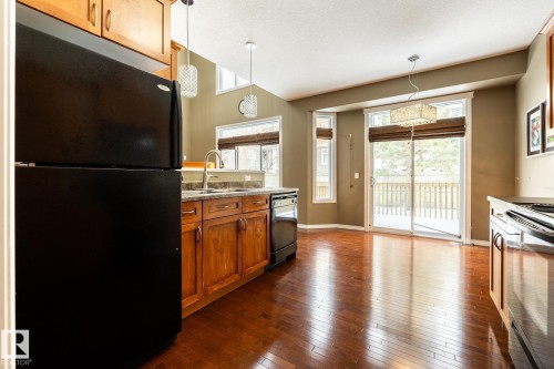 Kitchen featuring black appliances, wood finish cabinetry, dark wood-type flooring, and pendant lighting - 11622 11 Avenue, Edmonton, AB - Indoor Photo Showing Kitchen With Double Sink