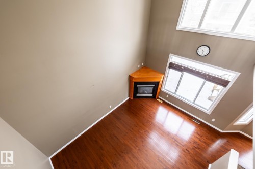 Unfurnished living room featuring a high ceiling, wood finished floors, and a fireplace - 11622 11 Avenue, Edmonton, AB - Indoor Photo Showing Other Room