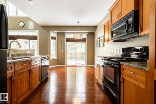 Kitchen with black appliances, wood finish cabinetry, dark wood-style flooring, and pendant lighting - 11622 11 Avenue, Edmonton, AB - Indoor Photo Showing Kitchen