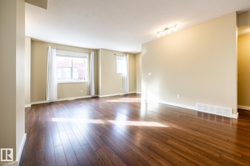 Empty room featuring dark wood finished floors, a textured ceiling, and rail lighting - 21 655 Watt Boulevard, Edmonton, AB - Indoor Photo Showing Other Room