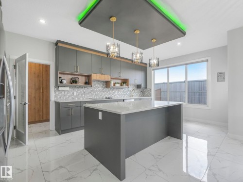 Kitchen featuring open shelves, gray cabinetry, a kitchen island, light stone countertops, and decorative backsplash - 1104 152 Avenue, Edmonton, AB - Indoor Photo Showing Kitchen With Upgraded Kitchen