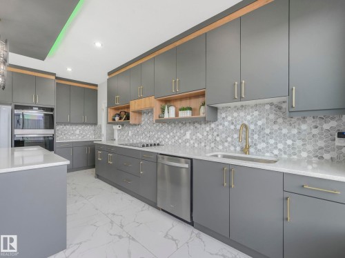 Kitchen with light stone counters, open shelves, light marble finish flooring, stainless steel appliances, and gray cabinetry - 1104 152 Avenue, Edmonton, AB - Indoor Photo Showing Kitchen With Upgraded Kitchen