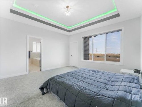 Carpeted bedroom with a tray ceiling and connected bathroom - 1104 152 Avenue, Edmonton, AB - Indoor Photo Showing Bedroom