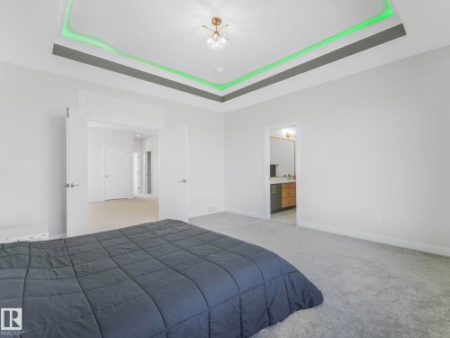 Unfurnished bedroom featuring light colored carpet, connected bathroom, and a tray ceiling - 1104 152 Avenue, Edmonton, AB - Indoor Photo Showing Bedroom