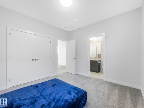 Bedroom with light colored carpet, connected bathroom, and a closet - 1104 152 Avenue, Edmonton, AB - Indoor Photo Showing Bedroom
