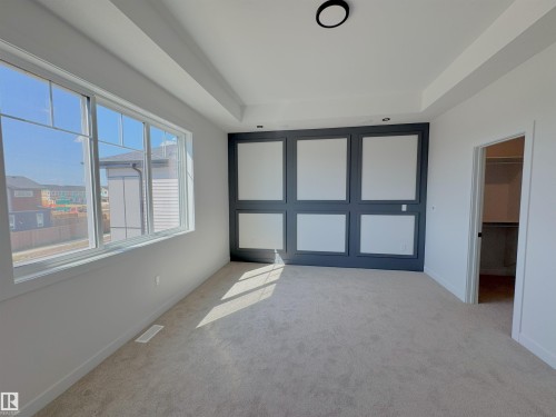 Unfurnished bedroom with a raised ceiling, light colored carpet, and a walk in closet - 7 Tilia Place, Spruce Grove, AB - Indoor Photo Showing Other Room