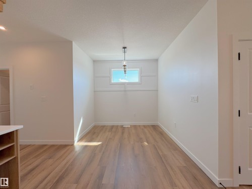 Unfurnished dining area featuring light wood-style flooring and a textured ceiling - 7 Tilia Place, Spruce Grove, AB - Indoor Photo Showing Other Room