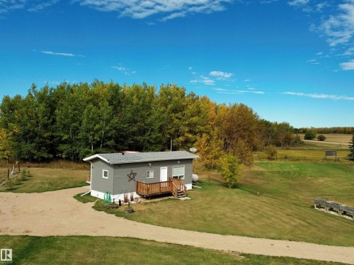 View of front of property with a front lawn, a deck, and dirt driveway - 106 57730 Range Road 30, Rural Barrhead County, AB - Outdoor