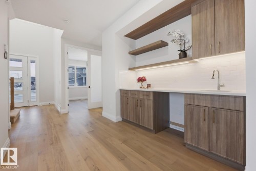 Bar area featuring open shelves, decorative backsplash, modern cabinets, light wood-type flooring, and brown cabinetry - 6704 Crawford Way, Edmonton, AB - Indoor