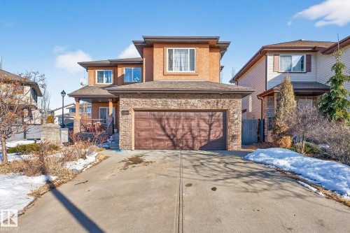 View of front of home with concrete driveway, a garage, stone siding, and roof with shingles - 1660 Malone Way, Edmonton, AB - Outdoor