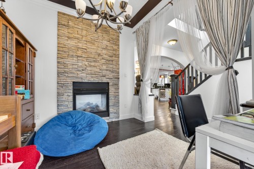 Office area with a fireplace, dark wood-type flooring, suspended lighting, and crown molding - 1660 Malone Way, Edmonton, AB - Indoor With Fireplace
