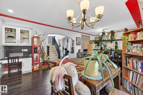 Dining space featuring arched walkways, dark wood-type flooring, a textured ceiling, suspended lighting, and ornamental molding - 1660 Malone Way, Edmonton, AB - Indoor Photo Showing Other Room