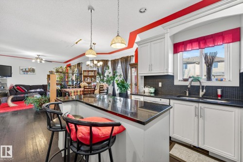 Kitchen featuring open floor plan, white cabinetry, backsplash, a center island, and ornamental molding - 1660 Malone Way, Edmonton, AB - Indoor Photo Showing Kitchen With Double Sink