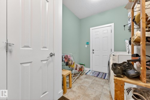 Mudroom with a textured ceiling, light tile patterned flooring, and washer and clothes dryer - 1660 Malone Way, Edmonton, AB - Indoor Photo Showing Other Room