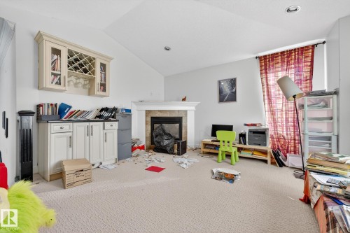 Playroom featuring carpet floors, a tile fireplace, and vaulted ceiling - 1660 Malone Way, Edmonton, AB - Indoor With Fireplace