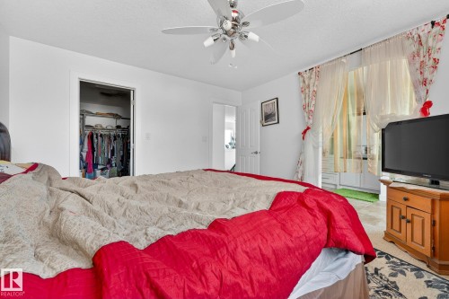 Bedroom with a ceiling fan, a textured ceiling, and a spacious closet - 1660 Malone Way, Edmonton, AB - Indoor Photo Showing Bedroom