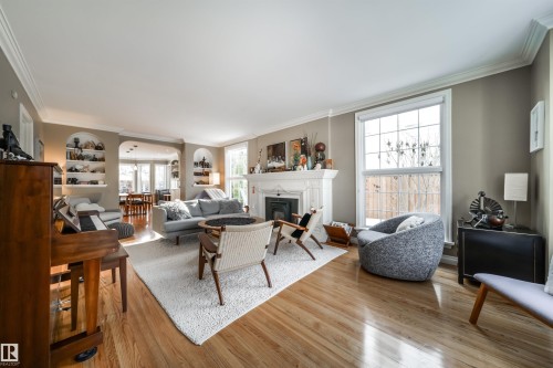 Living area featuring light wood-style flooring, ornamental molding, and a glass covered fireplace - 10445 134 Street, Edmonton, AB - Indoor Photo Showing Living Room With Fireplace