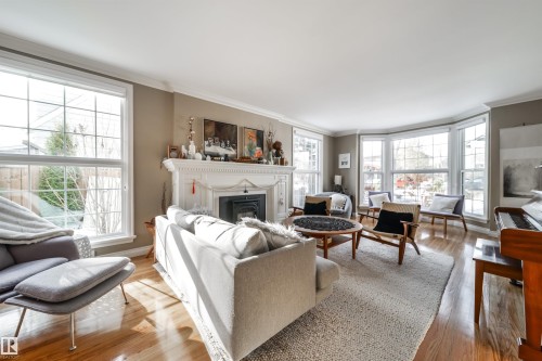 Living area featuring wood finished floors, crown molding, and a glass covered fireplace - 10445 134 Street, Edmonton, AB - Indoor Photo Showing Living Room With Fireplace
