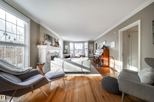 Living room with hardwood / wood-style floors, ornamental molding, and a fireplace - 10445 134 Street, Edmonton, AB - Indoor Photo Showing Living Room