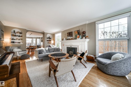 Living room with built in features, light wood-type flooring, crown molding, and a glass covered fireplace - 10445 134 Street, Edmonton, AB - Indoor Photo Showing Living Room With Fireplace