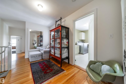 Sitting room with light wood-style flooring, a barn door, an upstairs landing, and separate washer and dryer - 10445 134 Street, Edmonton, AB - Indoor
