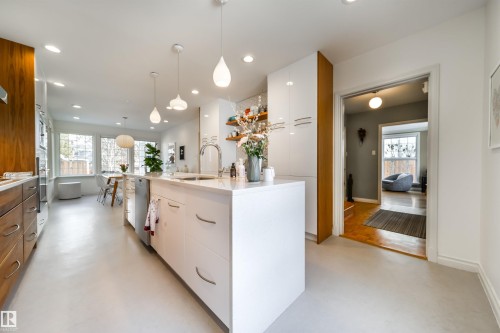 Kitchen featuring modern cabinets, a kitchen island with sink, light stone counters, dual tone cabinetry, and concrete floors - 10445 134 Street, Edmonton, AB - Indoor Photo Showing Kitchen With Upgraded Kitchen
