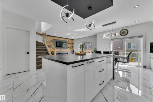 Kitchen with modern cabinets, a spacious island, a kitchen breakfast bar, dark countertops, and pendant lighting - 1809 18A Avenue, Edmonton, AB - Indoor