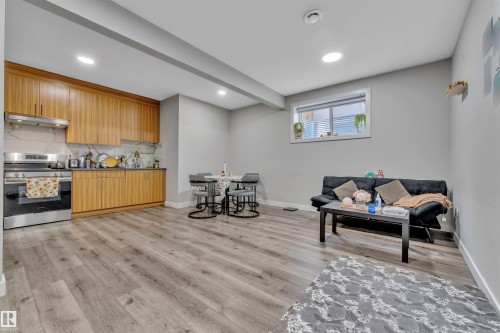 Interior space with stainless steel range with electric stovetop, light wood-style flooring, backsplash, wood finish cabinets, and beamed ceiling - 1809 18A Avenue, Edmonton, AB - Indoor