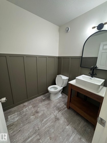 Bathroom with vanity, a textured ceiling, wainscoting, and a decorative wall - 17703 65 Street, Edmonton, AB - Indoor Photo Showing Bathroom
