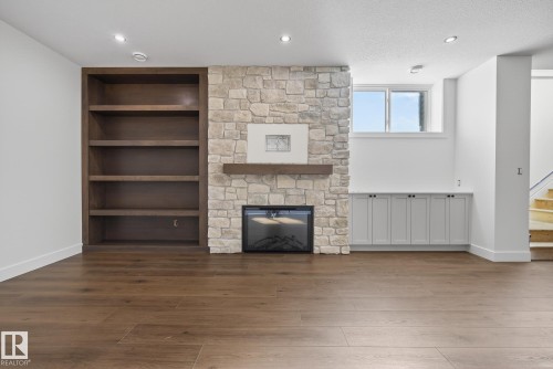 Unfurnished living room with wood finished floors, recessed lighting, a stone fireplace, built in features, and a textured ceiling - 149 Eastgate Way, St. Albert, AB - Indoor With Fireplace