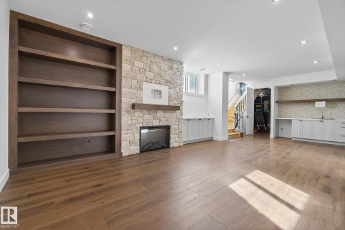 Unfurnished living room featuring built in shelves, a fireplace, and dark wood-type flooring - 149 Eastgate Way, St. Albert, AB - Indoor With Fireplace