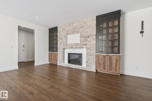 Unfurnished living room featuring dark wood finished floors, a fireplace, and a textured ceiling - 149 Eastgate Way, St. Albert, AB - Indoor Photo Showing Living Room With Fireplace