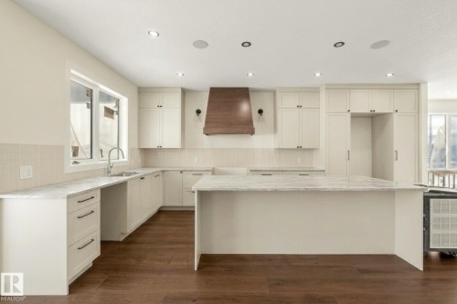 Kitchen with light stone countertops, a center island, dark wood-type flooring, decorative backsplash, and white cabinets - 149 Eastgate Way, St. Albert, AB - Indoor Photo Showing Kitchen With Upgraded Kitchen