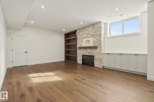 Unfurnished living room with a stone fireplace, light wood-type flooring, built in features, and recessed lighting - 149 Eastgate Way, St. Albert, AB - Indoor With Fireplace