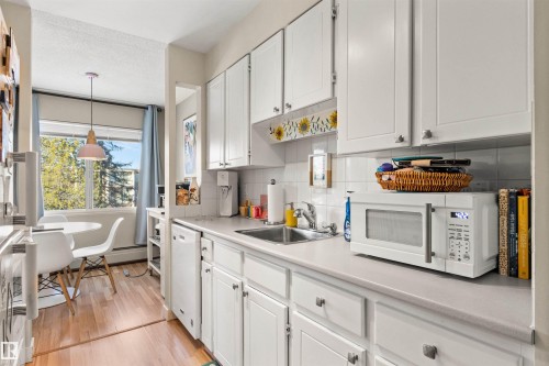Kitchen with white cabinetry, light countertops, white appliances, light wood-type flooring, and backsplash - 304 11420 40 Avenue Nw, Edmonton, AB - Indoor Photo Showing Kitchen