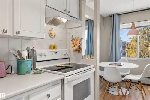 Kitchen featuring electric range, white cabinets, light countertops, and light wood-style floors - 304 11420 40 Avenue Nw, Edmonton, AB - Indoor Photo Showing Kitchen
