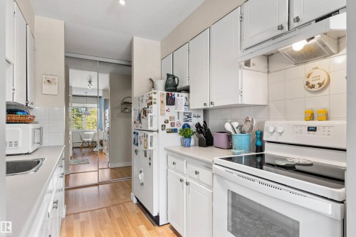 Kitchen featuring white appliances, light countertops, exhaust hood, white cabinetry, and light wood finished floors - 304 11420 40 Avenue Nw, Edmonton, AB - Indoor Photo Showing Kitchen