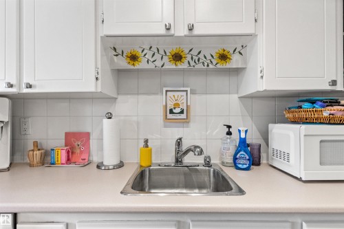 Kitchen with white cabinetry, decorative backsplash, and white microwave - 304 11420 40 Avenue Nw, Edmonton, AB - Indoor Photo Showing Kitchen