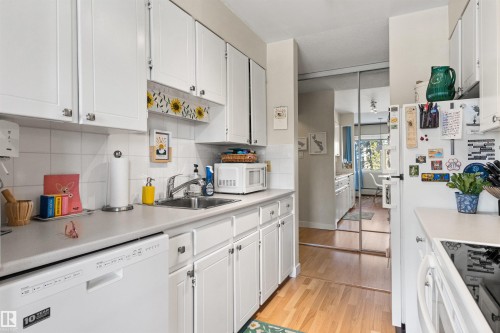 Kitchen with white cabinets, white appliances, light countertops, and light wood-type flooring - 304 11420 40 Avenue Nw, Edmonton, AB - Indoor Photo Showing Kitchen