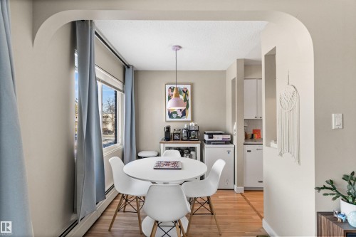 Dining room featuring a baseboard radiator, light wood finished floors, arched walkways, and a textured ceiling - 304 11420 40 Avenue Nw, Edmonton, AB - Indoor Photo Showing Dining Room