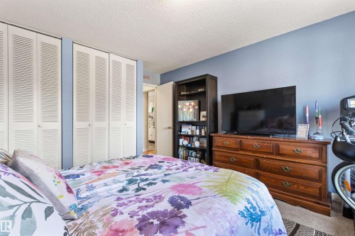 Carpeted bedroom featuring two closets and a textured ceiling - 304 11420 40 Avenue Nw, Edmonton, AB - Indoor Photo Showing Bedroom