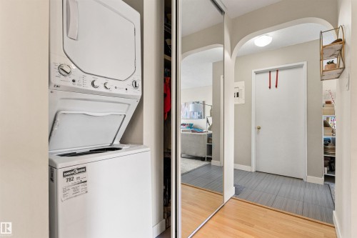Laundry area featuring arched walkways, stacked washer and clothes dryer, and light wood-style flooring - 304 11420 40 Avenue Nw, Edmonton, AB - Indoor Photo Showing Laundry Room