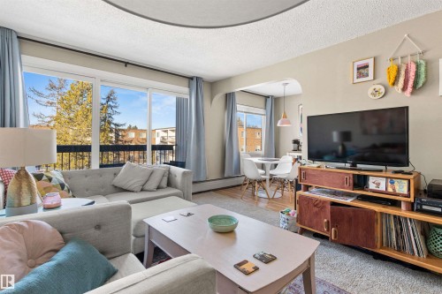 Living area featuring a textured ceiling, a baseboard radiator, and light wood finished floors - 304 11420 40 Avenue Nw, Edmonton, AB - Indoor Photo Showing Living Room