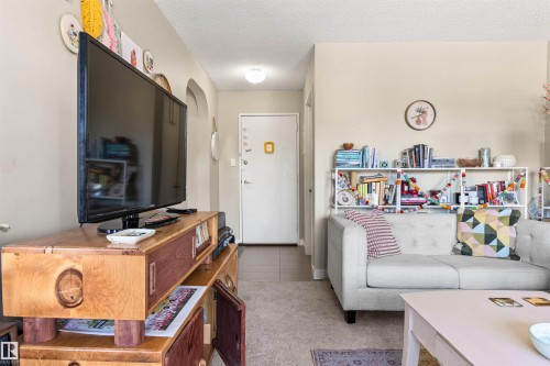 Living room with light colored carpet, a textured ceiling, and arched walkways - 304 11420 40 Avenue Nw, Edmonton, AB - Indoor