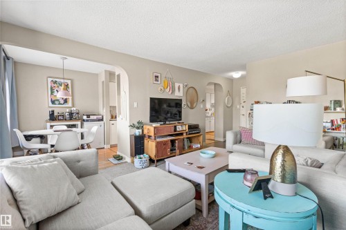 Living room with arched walkways, a textured ceiling, and wood finished floors - 304 11420 40 Avenue Nw, Edmonton, AB - Indoor Photo Showing Living Room