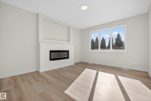 Unfurnished living room with light wood-type flooring and a glass covered fireplace - 22 Grayson Green, Stony Plain, AB - Indoor Photo Showing Living Room With Fireplace