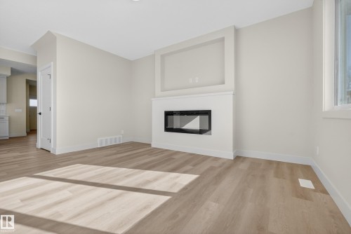 Unfurnished living room with light wood-type flooring and a glass covered fireplace - 22 Grayson Green, Stony Plain, AB - Indoor Photo Showing Living Room With Fireplace