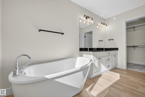Bathroom featuring vanity, light wood-style flooring, a freestanding tub, and a spacious closet - 22 Grayson Green, Stony Plain, AB - Indoor Photo Showing Bathroom