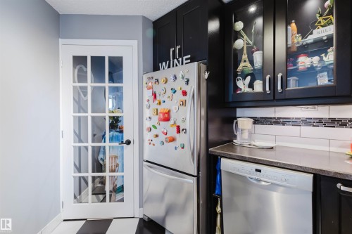 Kitchen featuring glass fronted cabinets, stainless steel appliances, dark cabinets, and dark stone counters - 1803 10149 Saskatchewan Drive, Edmonton, AB - Indoor